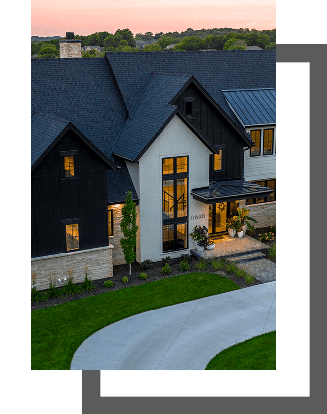 A large white house with black trim and a green driveway.